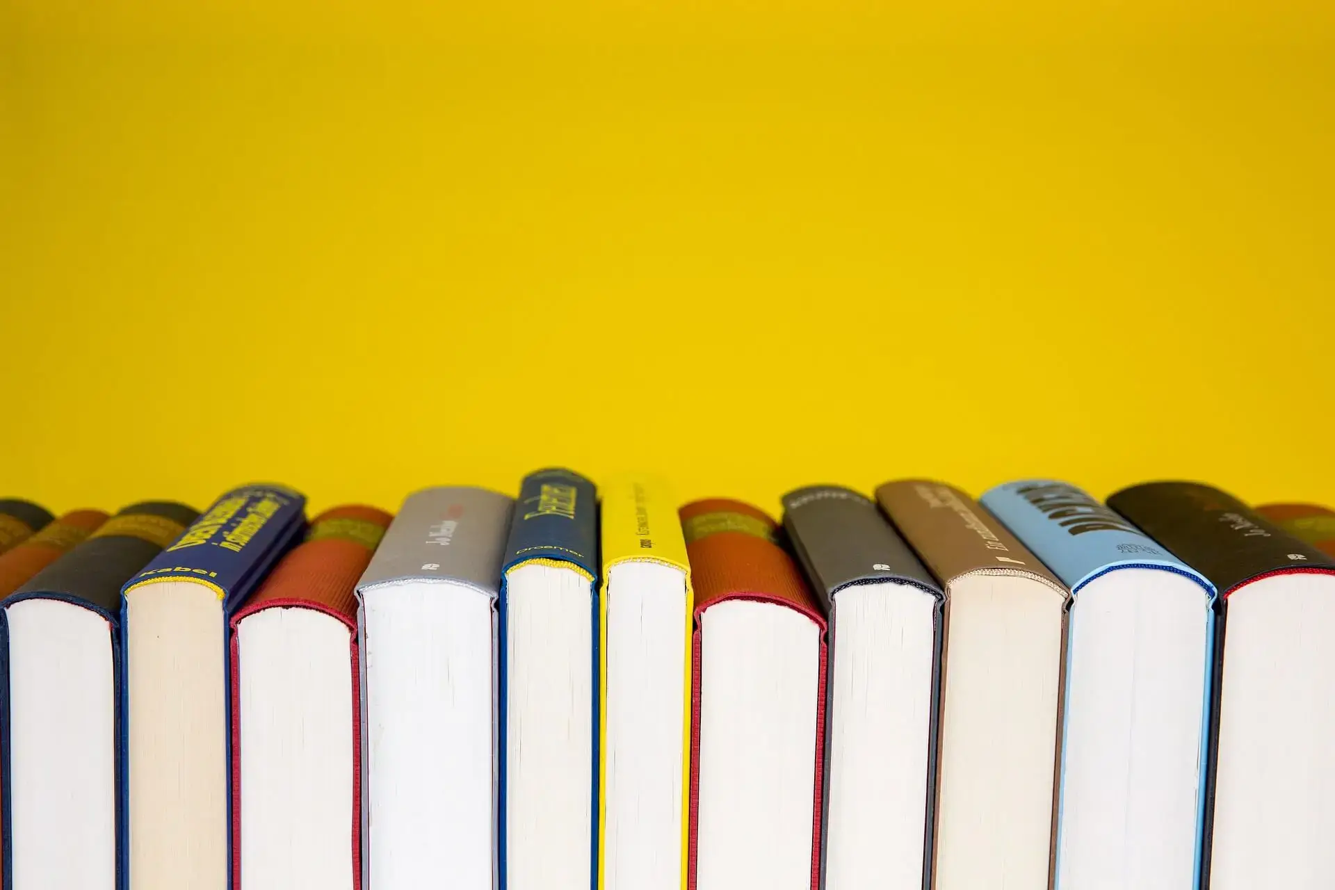 Library books spine up in front of yellow background