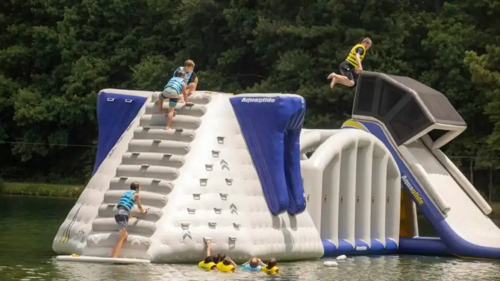 Children climbing on aqua park in lake.