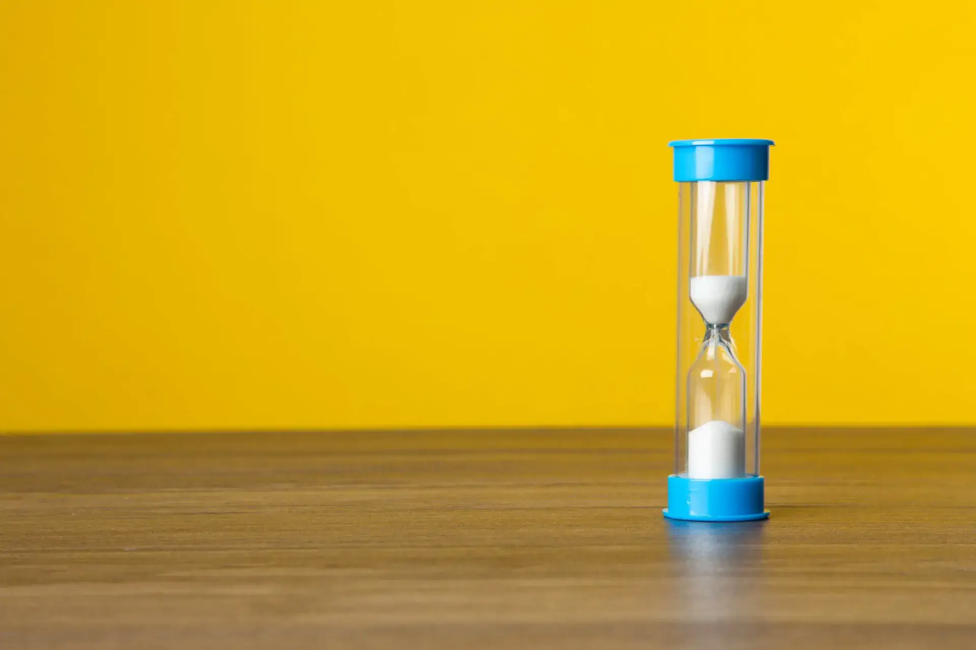 Sand timer on yellow background