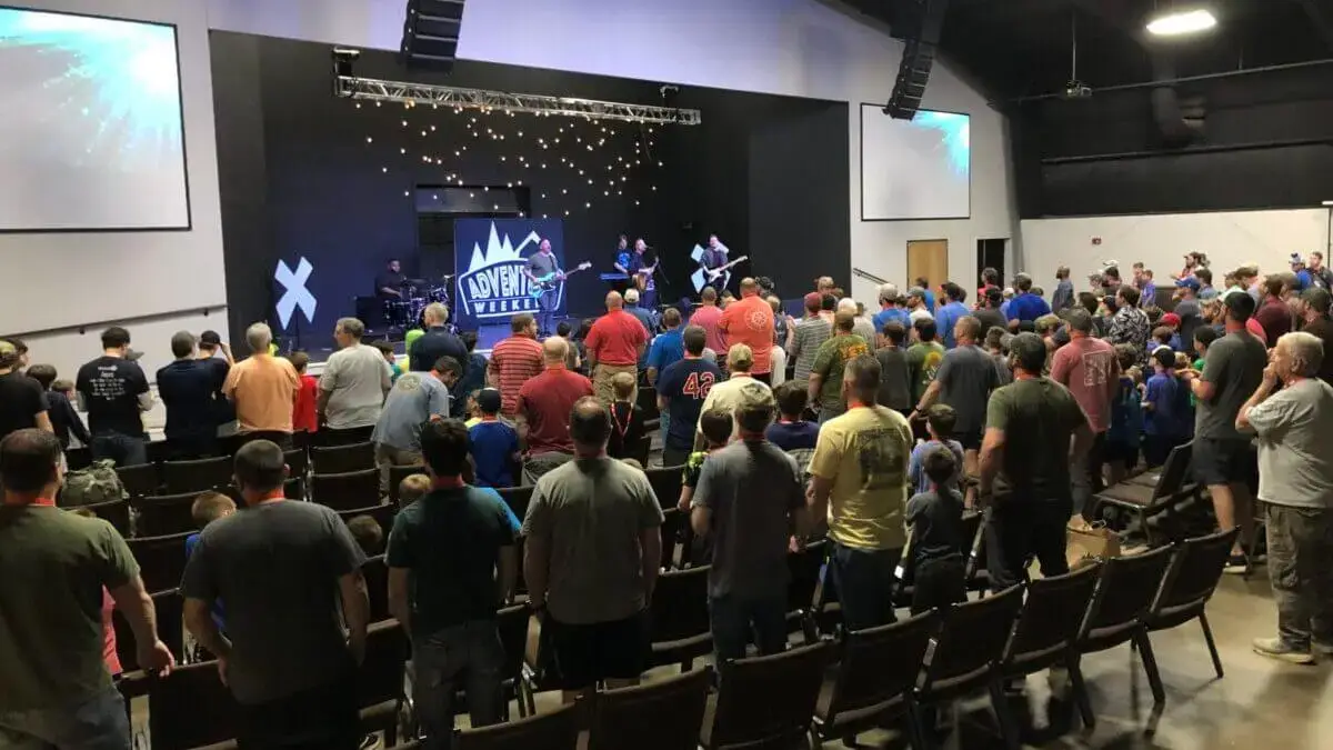 Fathers and sons standing together during worship with band on stage