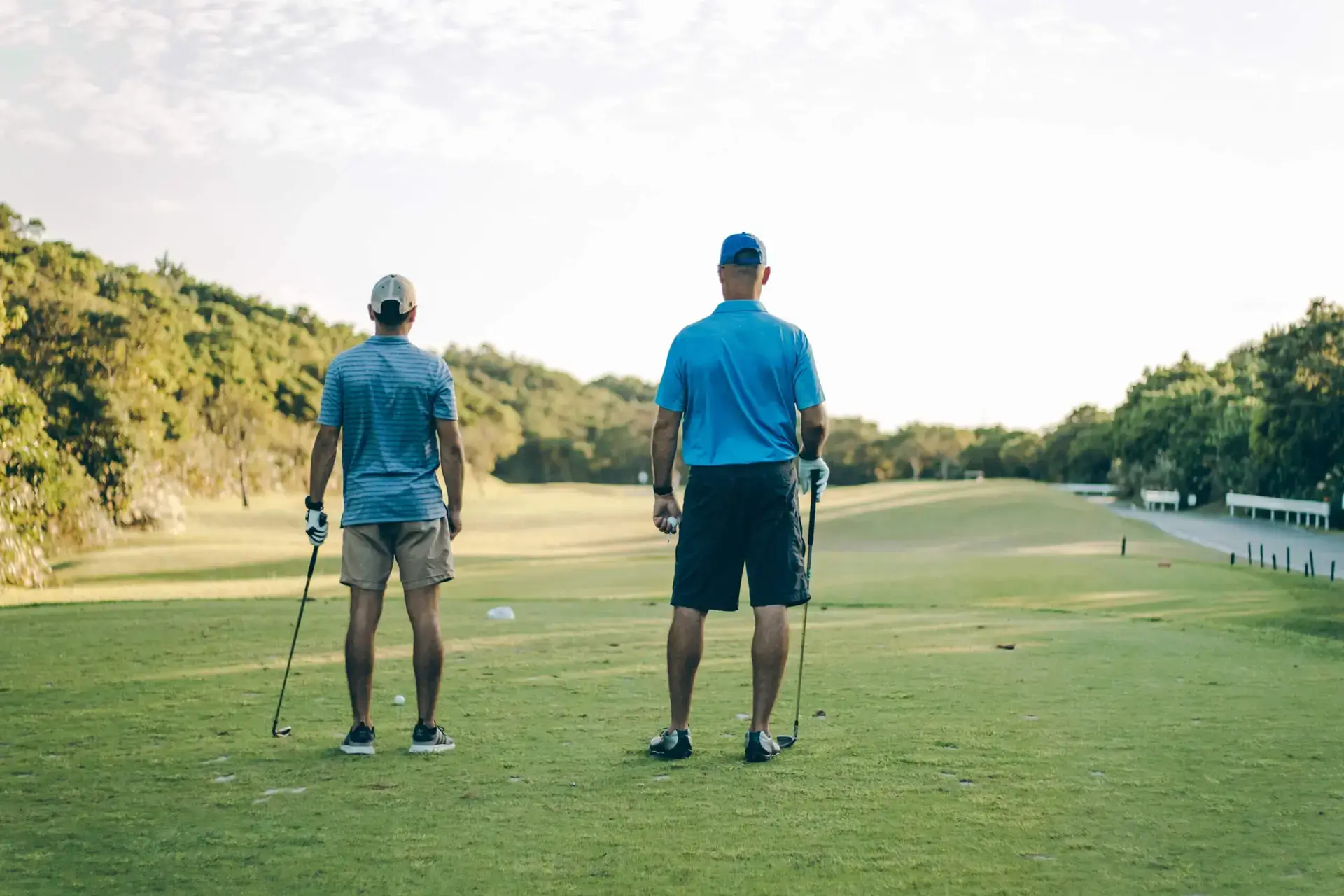 Two men look down a fairway while playing golf