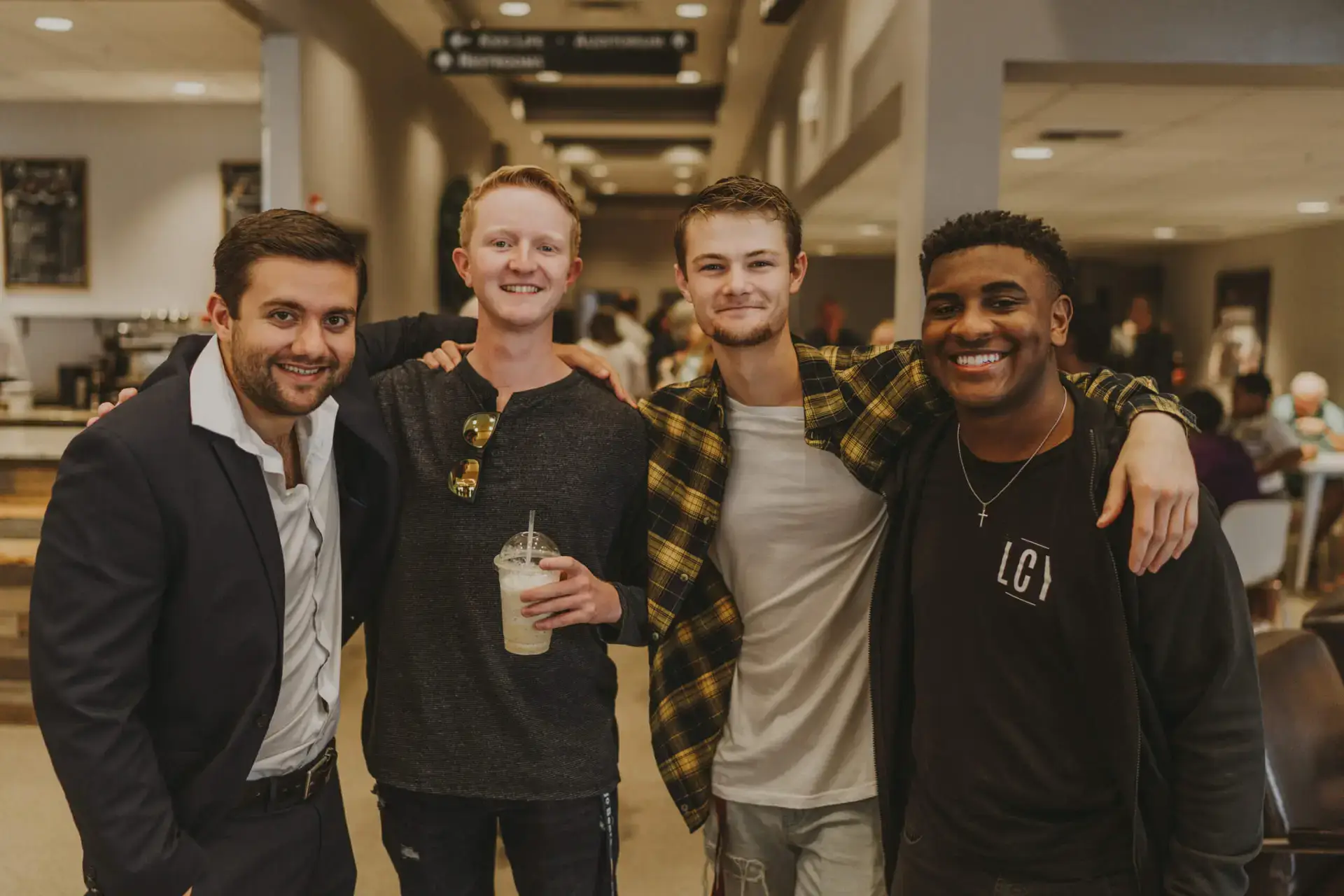 Four young men pose for a picture with arms around one another's shoulders