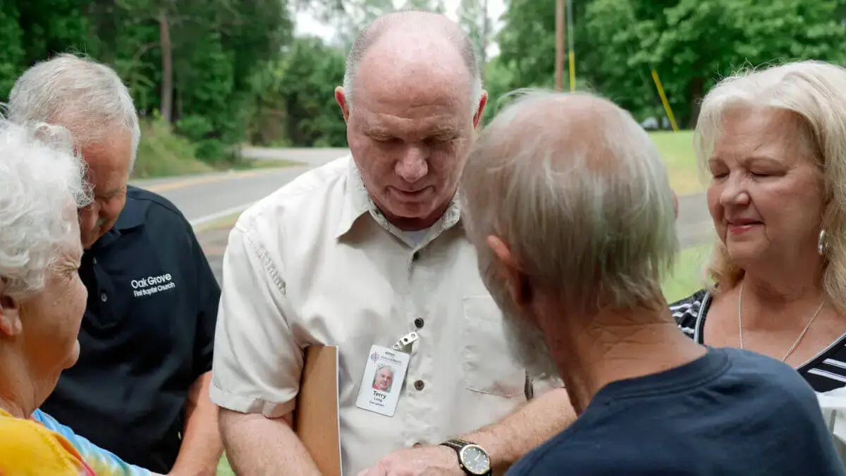 Man prays over fellow team members during evangelistic event