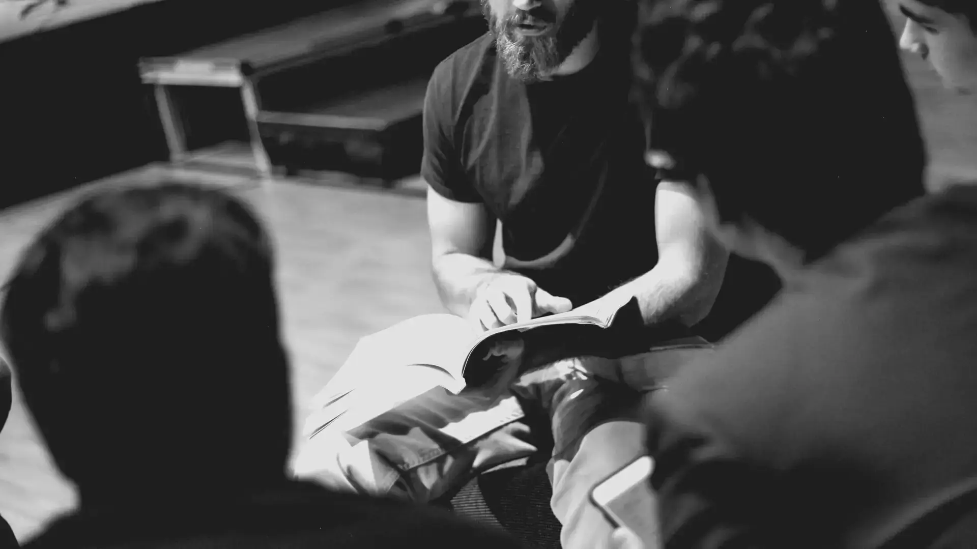 Man sitting with an open bible discipling three other men