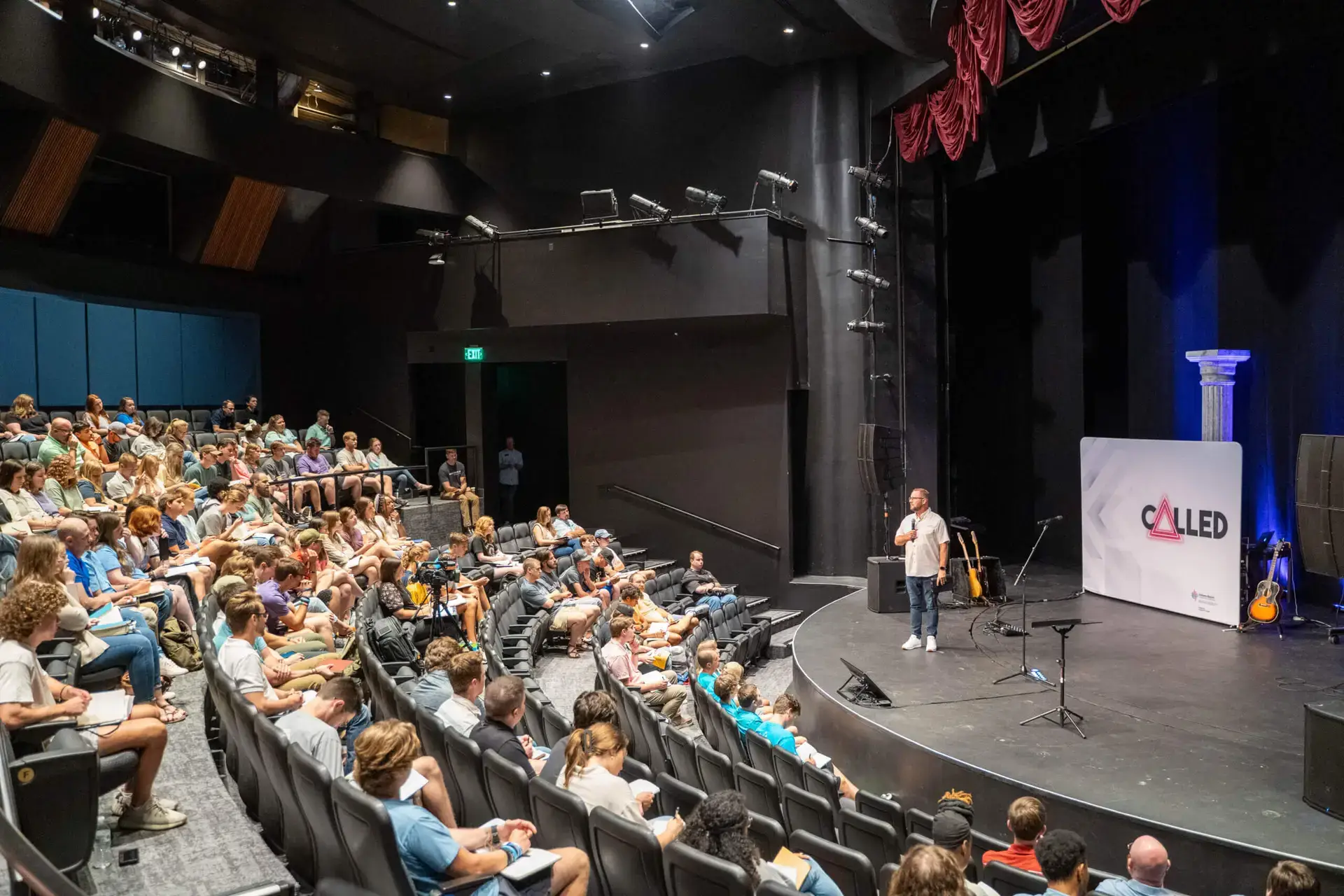 Students sitting in auditorium listening to speaker Jamie Dew at Called Conference