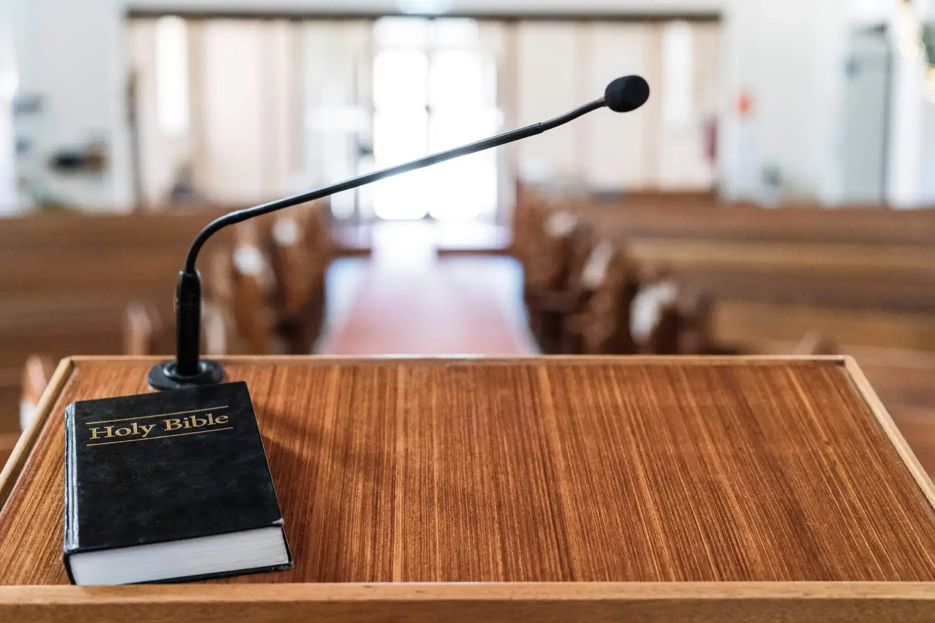 Bible on church pulpit, with light coming through the front doors