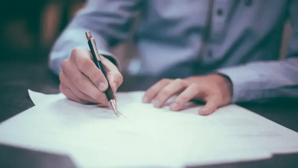 Male hand holding mechanical pencil filling out a report on paper