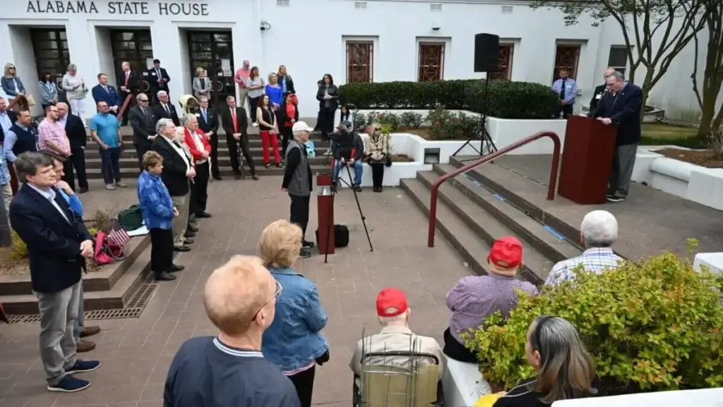 Group of people stand on steps near Alabama State House praying