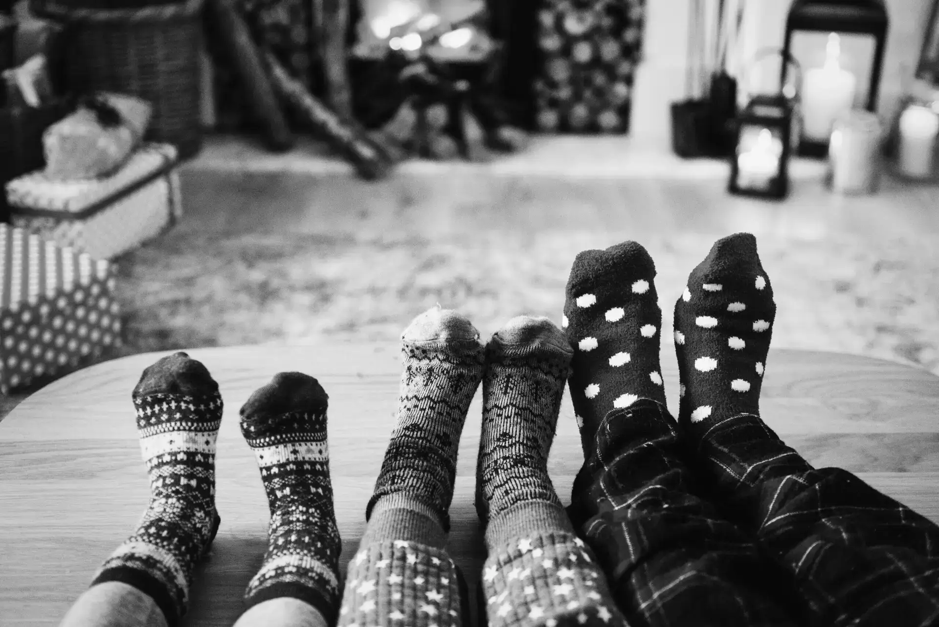 Black and white photo of family sitting with feet stretched out wearing Christmas socks