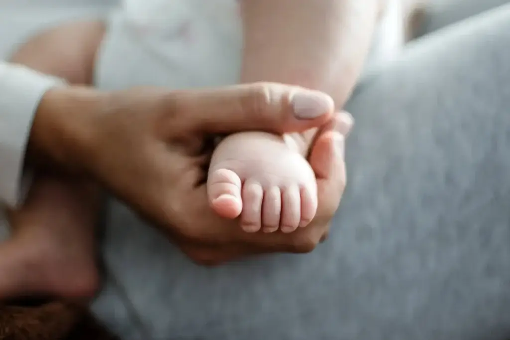 Mother holding in hands feet of newborn baby