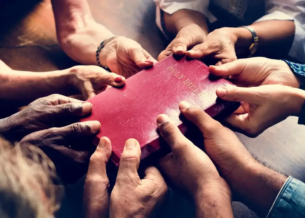 Group of people holding red bible with both hands