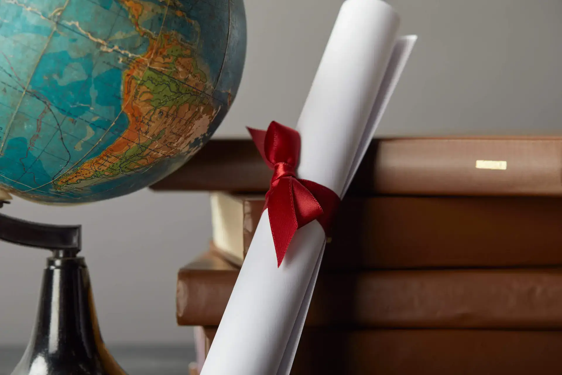 Brown books, globe and diploma with red ribbon on it