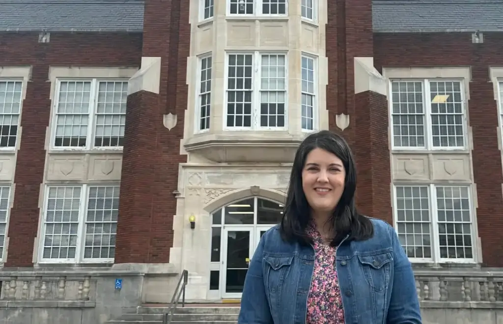 Shannon Hughes poses in front of collegiate building