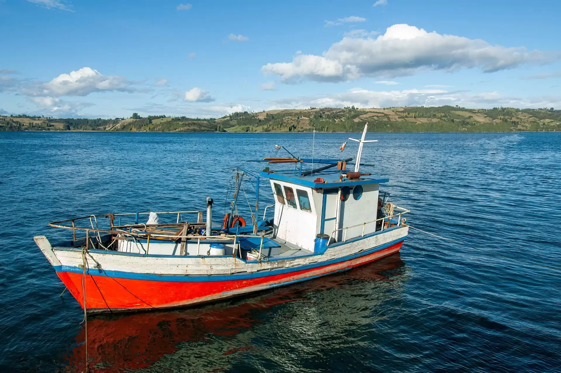 A boat sailing on the water surface with landscape in the background