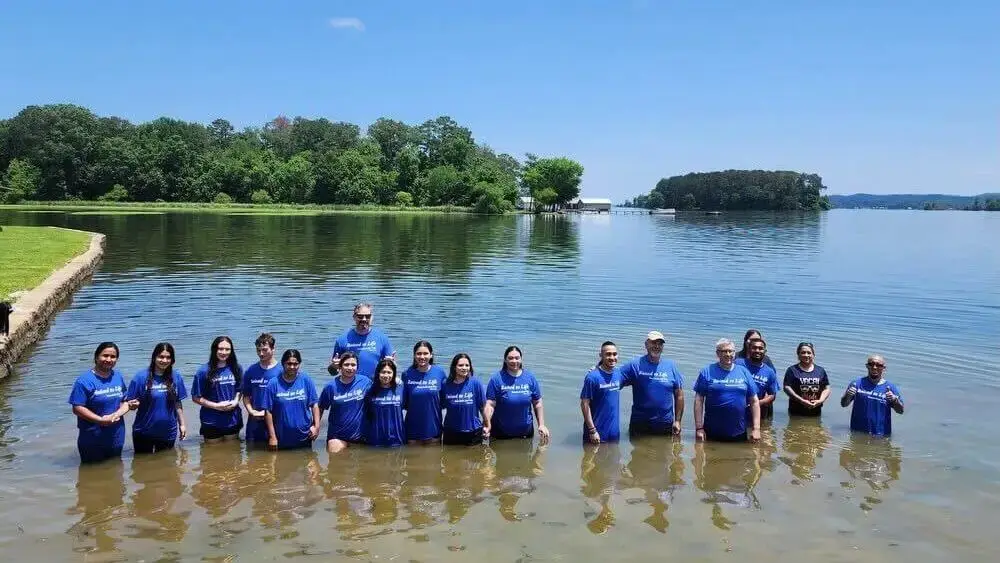 Men and women stand in a lake where they were baptized.