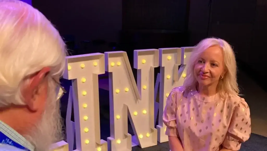 Jana Magruder sitting in front of large light up letters.