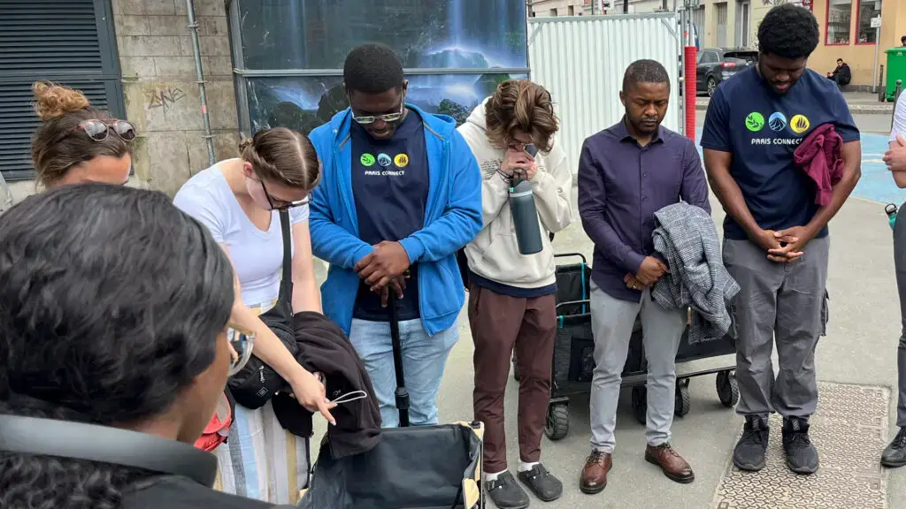 A diverse group of Olympic missionary volunteers gather in prayer in Paris