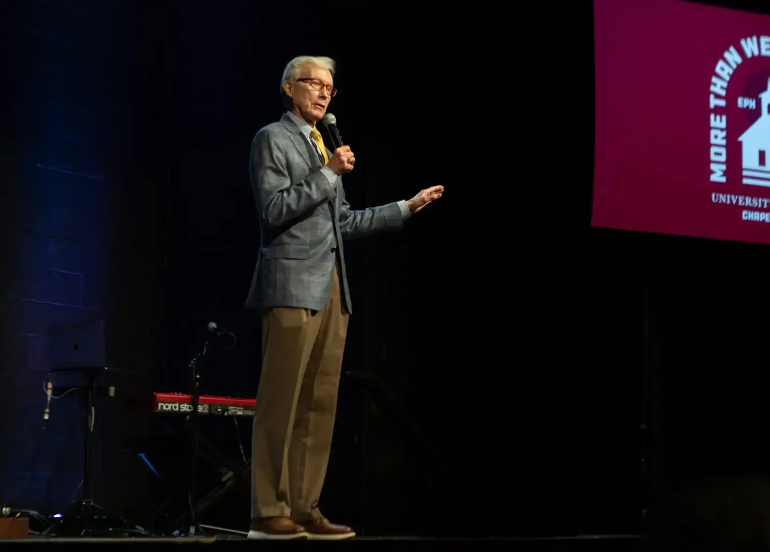 Rick Lance standing on stage with dark background at the University of Mobile Chapel