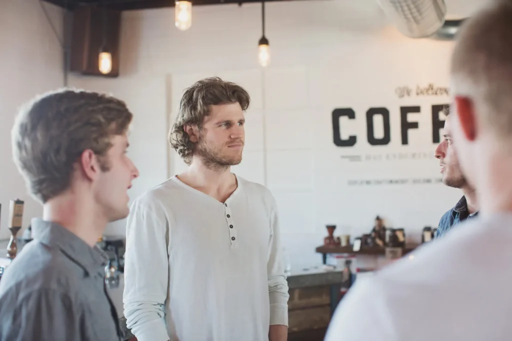 Group of men stand in a circle talking at a coffee shop