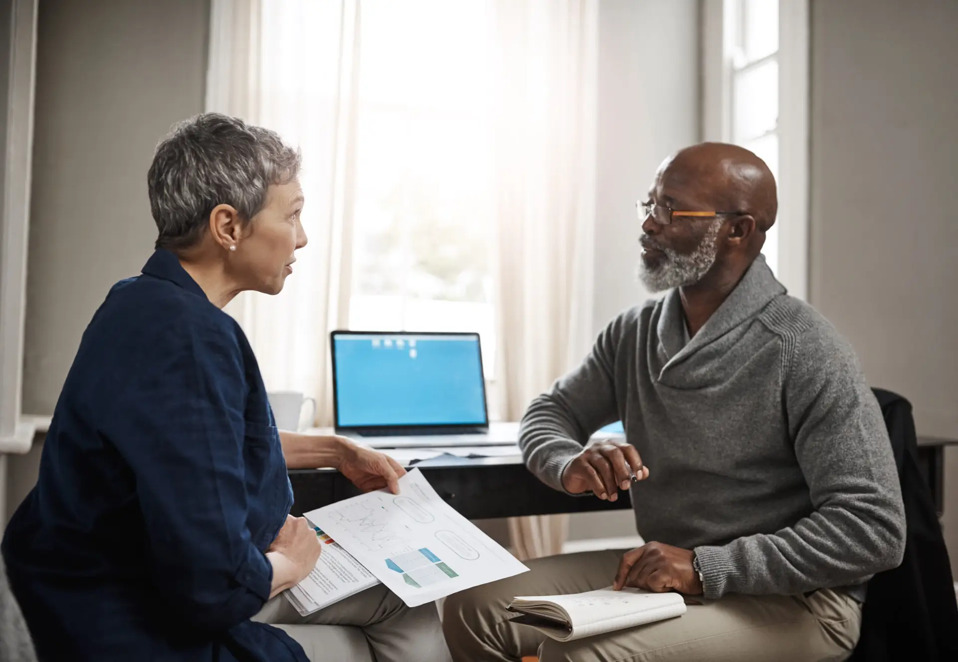 Man and woman sit facing each other discussing retirement