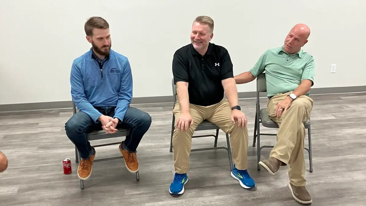 Three men sit in chairs leading a panel discussion