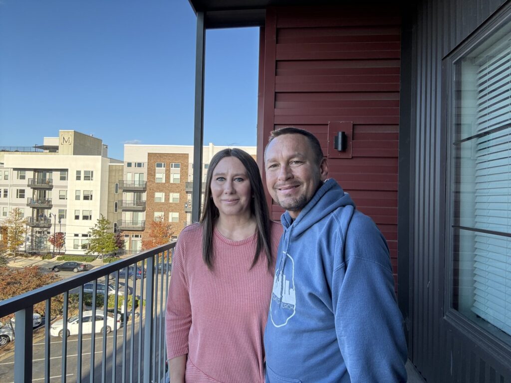 Will and Missy Faulkenberry stand on a balcony of an apartment