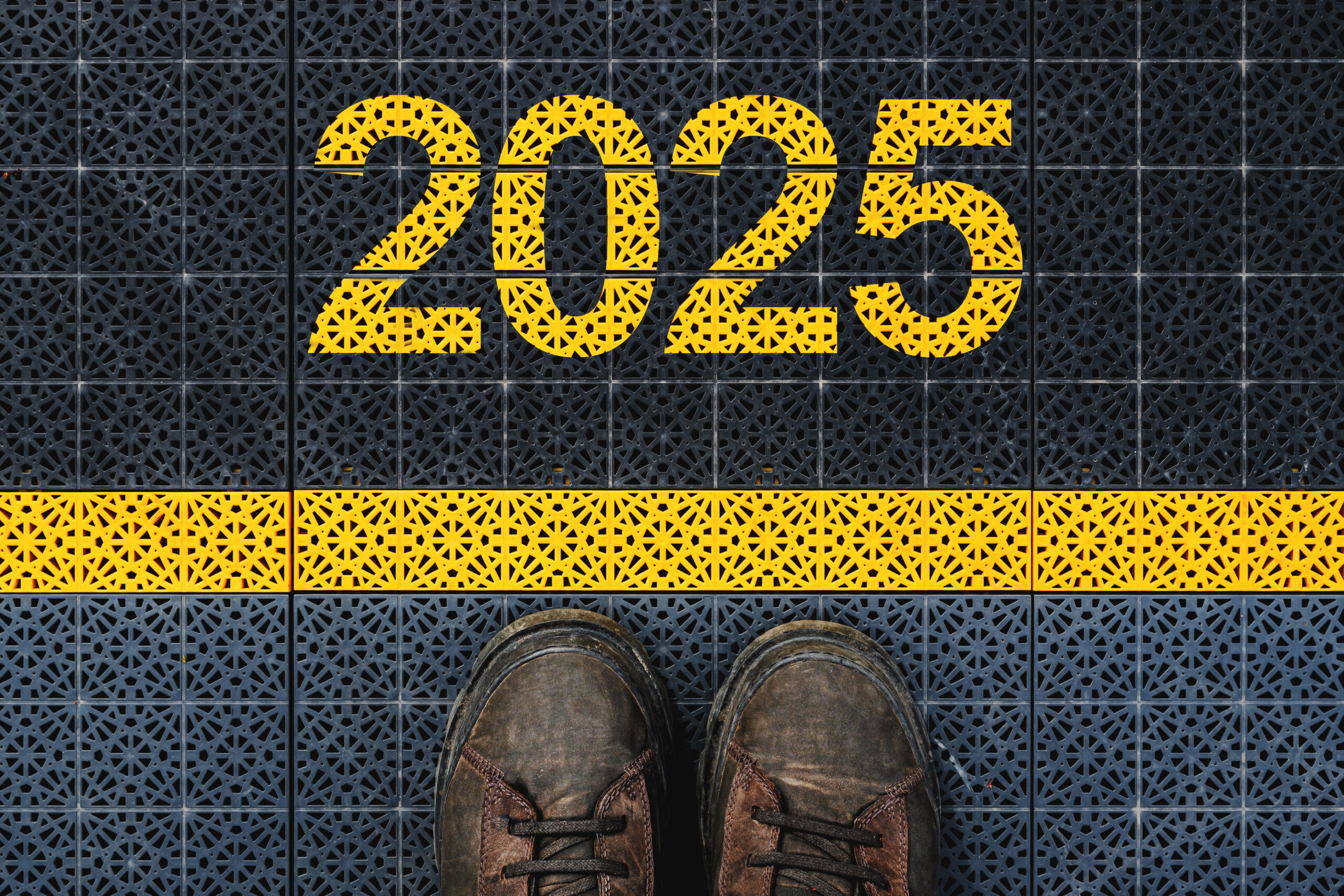 Man standing on outdoor sport court plastic flooring behind yellow line with a yellow 2025 above it