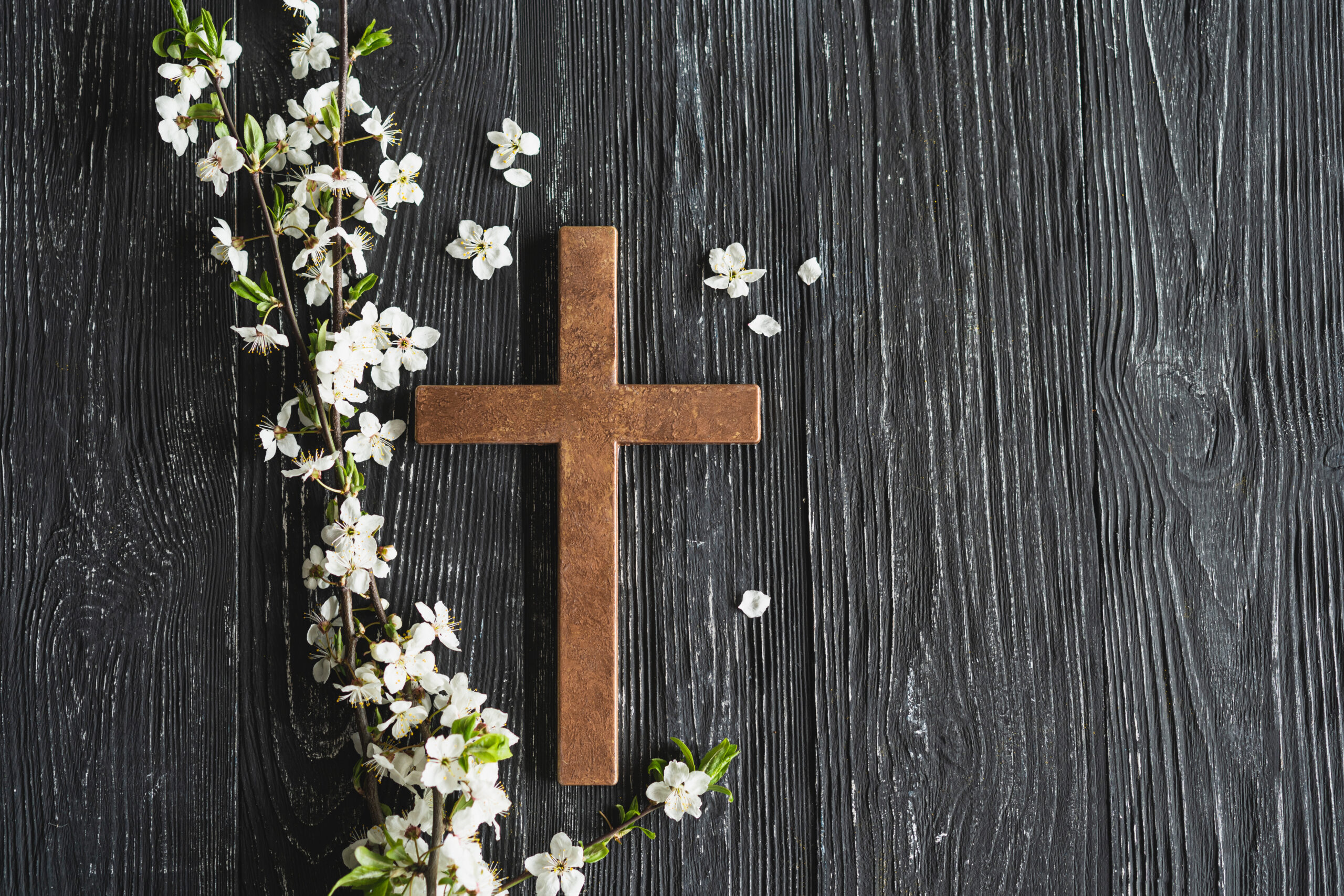 Easter cross, symbolizing the death and resurrection of Jesus Christ, spring flowers on a wood background.